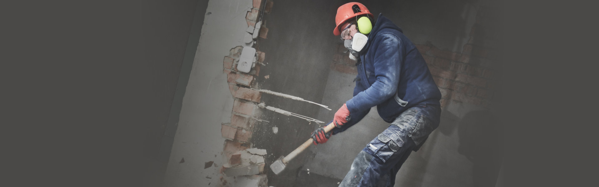 worker with sledgehammer destroying wall